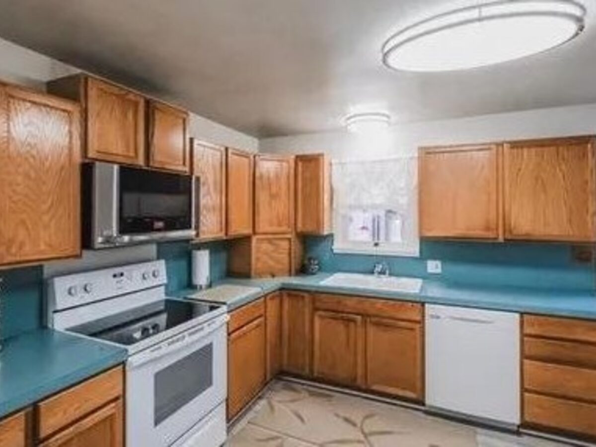 Kitchen before remodel — original teal counters and oak cabinets